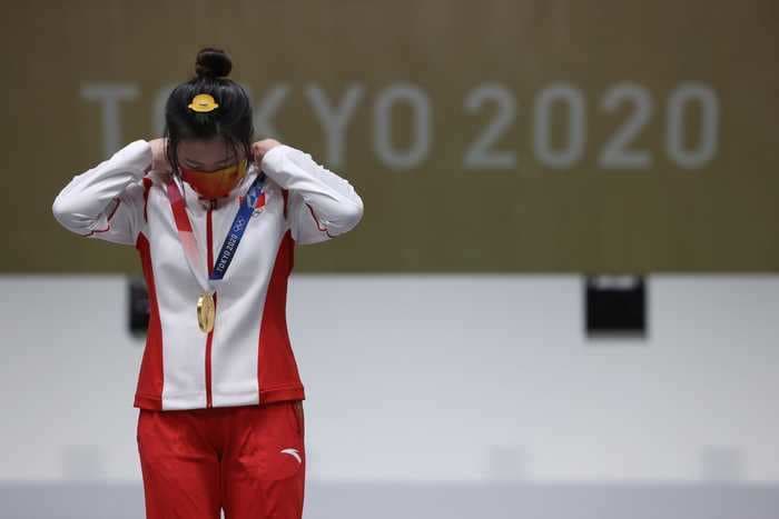 The winner of the Tokyo Olympics' first gold had to put her medal around her own neck and sing her national anthem behind a mask