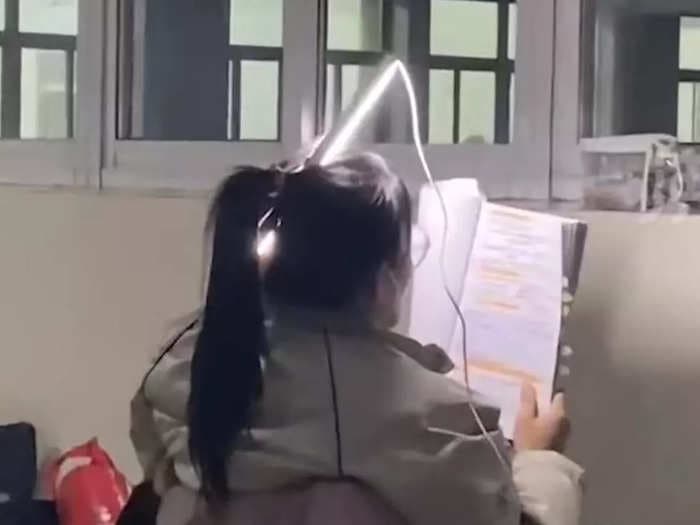 A woman in China stuck a fluorescent light through her ponytail to keep studying when the university lights went out, and the photo has become a viral symbol for hard work