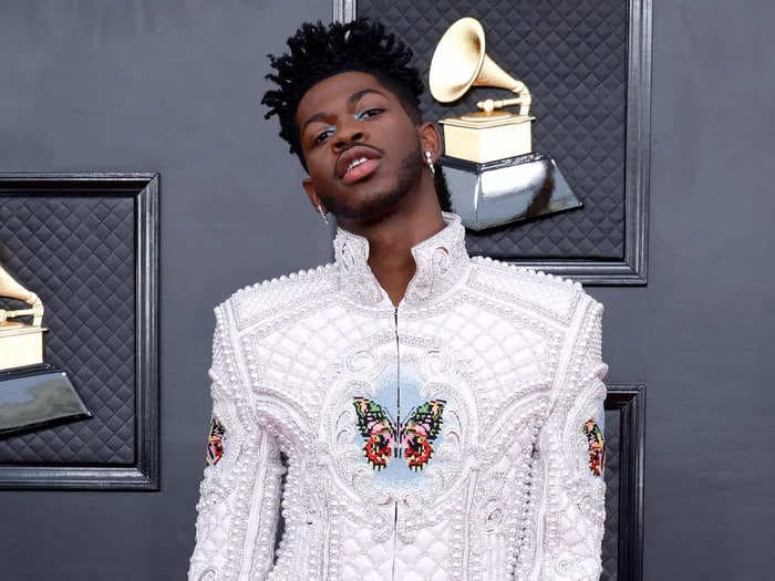 Take a look at Lil Nas X's daring looks at the 2022 Grammys, from a pearl suit to an all-black ensemble with a dazzling cape