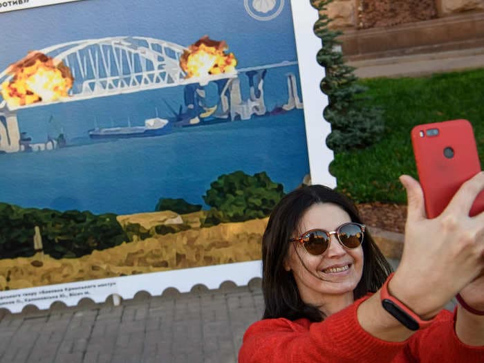 Ukrainians are posing with a giant postage stamp depicting the blown up bridge linking Russia and Crimea