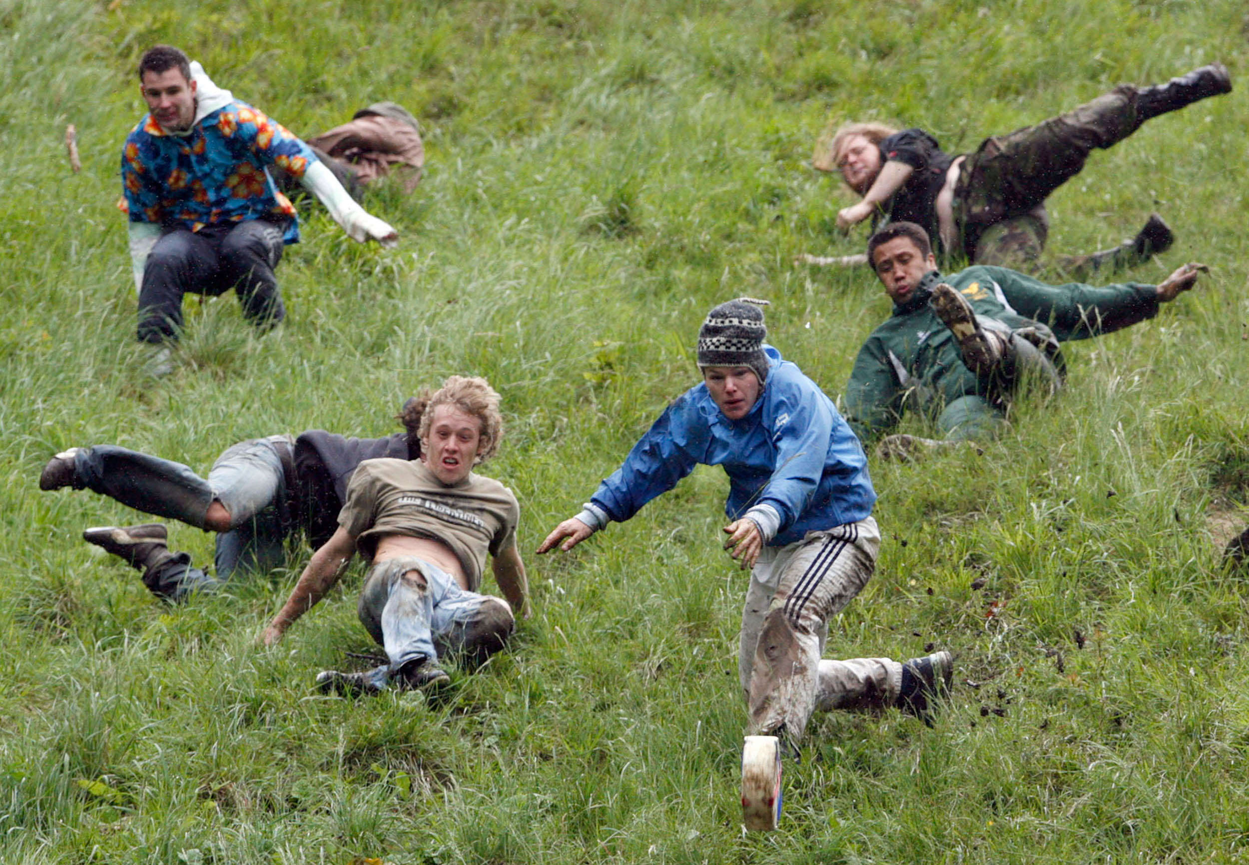 Кубарем. «Cheese Rolling Championship» — сырная гонка. Человек бежит в гору. Чемпионат по катанию сыра. Куперсхилдская сырная гонка травмы.