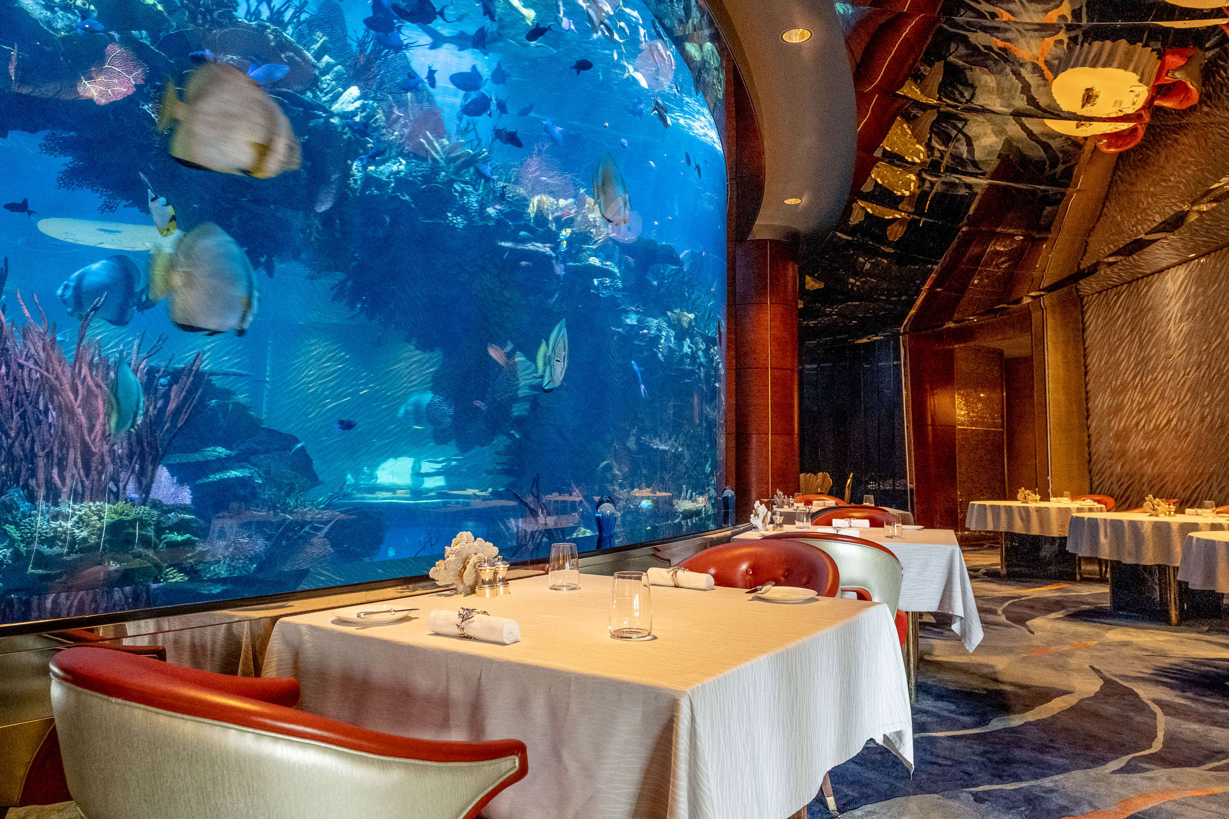 The dining room of Al Mahara wraps around a floor-to-ceiling 260,000 ...