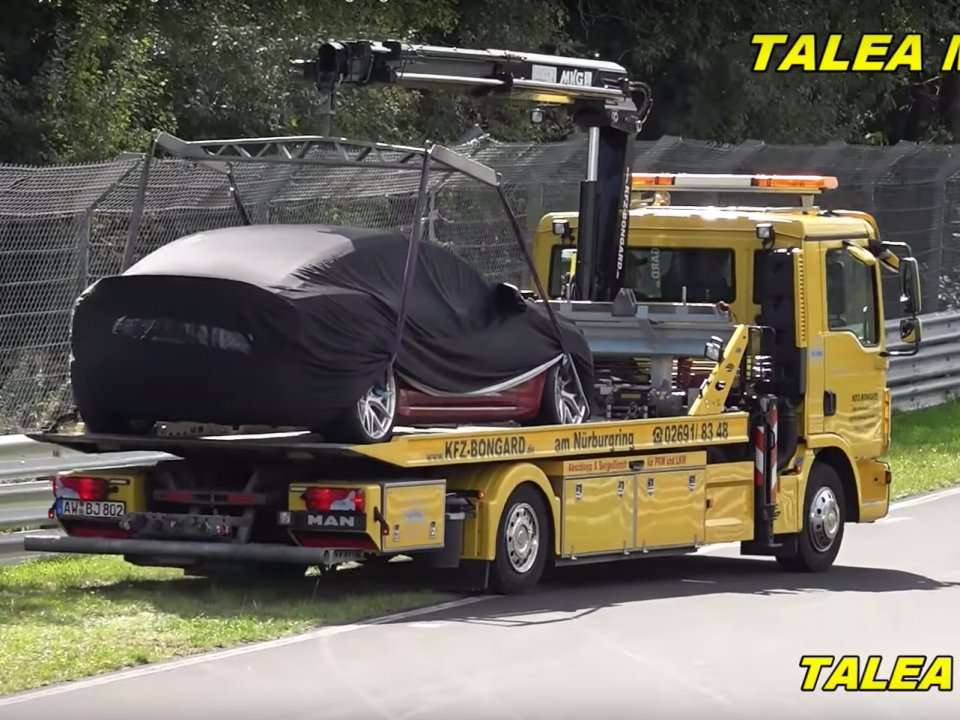 A Tesla Model S sat on a tow truck at the Nurburgring as a Porsche