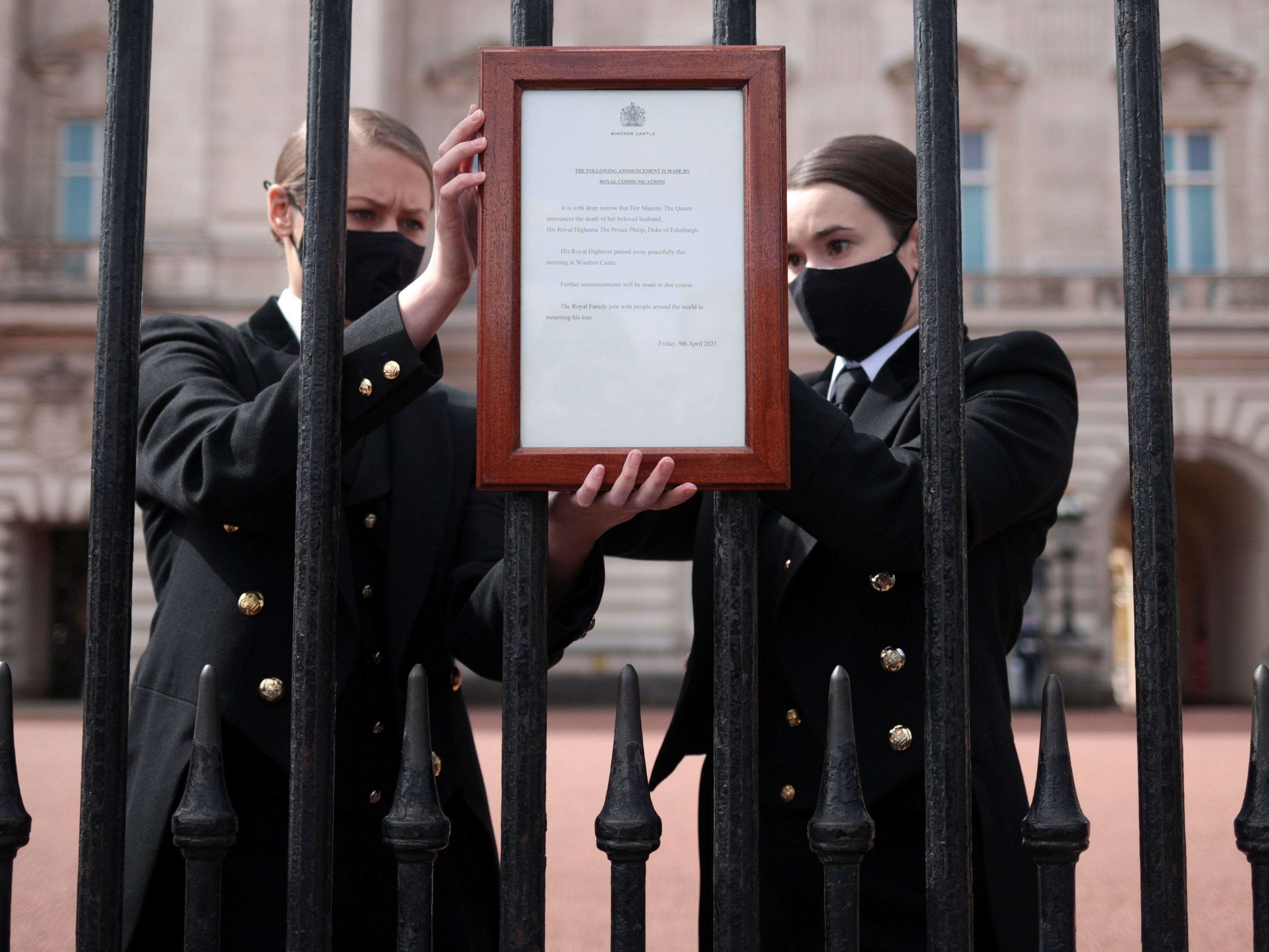 Photos show Buckingham Palace staff hanging a sign on its front gates