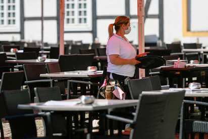 A waitress walks past empty chairs and tables in a restaurant in the city of Rheda-Wiedenbrueck, western Germany on June 23, 2020.